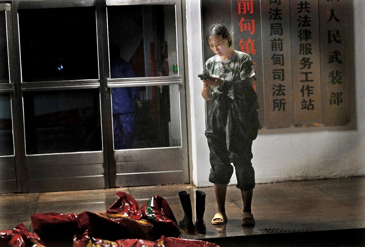  郑丹丹紧盯手机工作群动态，实时关注最新雨情和调度指令。抚顺市委宣传部供图
